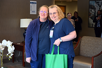 Melissa Lewis, director of infection prevention for Ashe Memorial Hospital congratulates Ruth Ann Hill, RN, after being named this year's DAISY Award winner.Two nurses standing together and smiling for a photo.