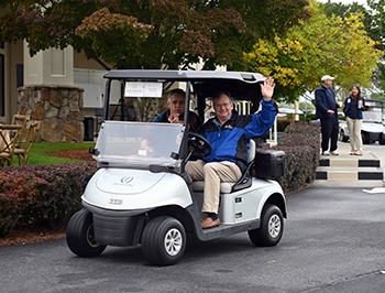 Two men riding in golf cart.