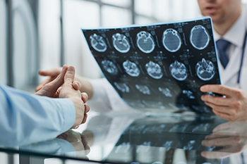 Male Radiologists holding up an MRI scan X-RAY&apos;s of a male patients brain.