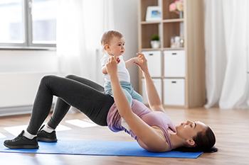 A picture of a mother doing pelvic floor exercises while holding her toddler.